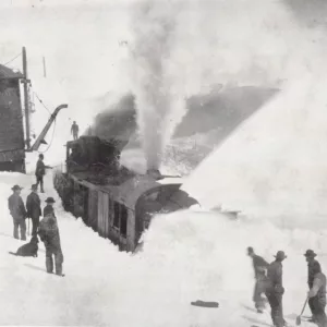 Men attempt to dig out a railroad locomotive from deep snow.