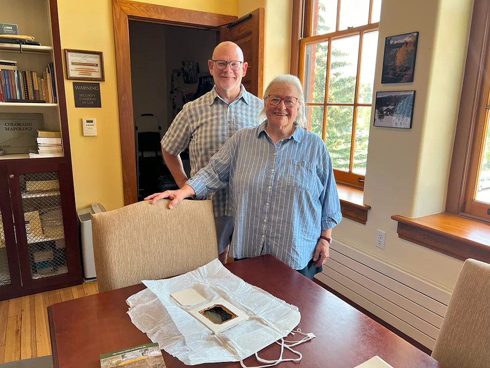 Kirby Lambert and Becca Kohl stand behind a table in the Breckenridge History Archives. On the table sits an 1862 ambrotype.